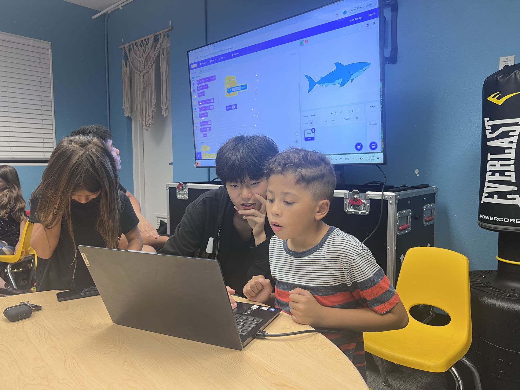 Children and a volunteer working together on a laptop