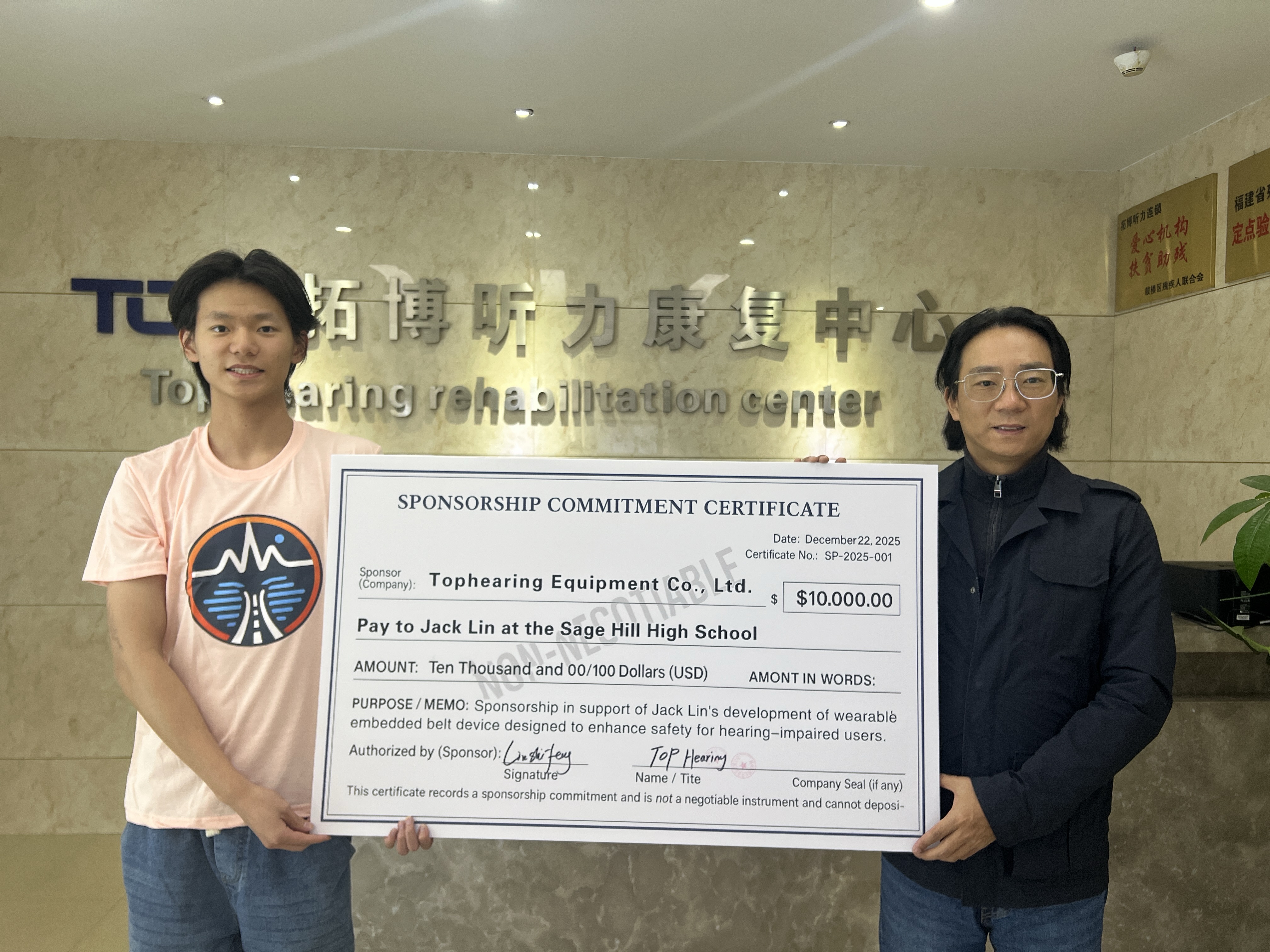 Two people holding a sponsorship commitment certificate at a hearing rehabilitation center